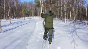 Pensioner walks through the winter forest on skis at a fast