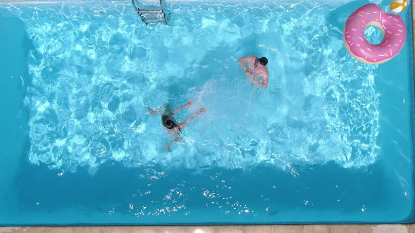 Aerial - Top down view of couple having splash war in the pool. A fun summer day in the pool at home | Shutterstock HD Video #1009029731