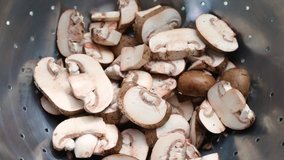 Video of rinsing sliced baby bella mushrooms in a stainless steel colander with water.