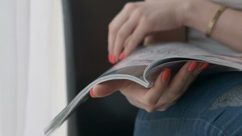Woman Hands holding open holding magazine. Close up