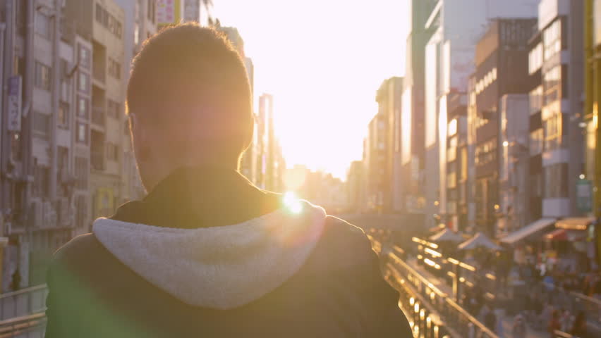 Tourist watching sunset over busy canal in Japan.
