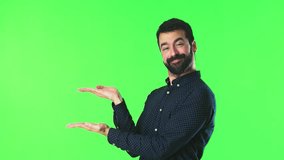 Handsome man holding copyspace imaginary on the palm on green screen chroma key