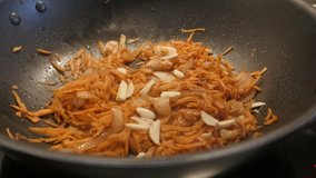 Adding of garlic to bulb onion and grated carrot close-up 4K 2160p 30fps UltraHD footage - Fried vegetable mix in the wok 3840X2160 UHD video