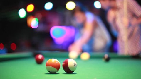 Playing pool billiards in a night bar with bokeh lights on the background. 1920x1080