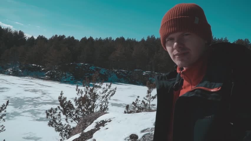 the guy is looking into the distance in the winter forest
