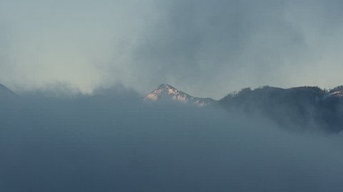 Morning shot of the mist and clouds in winter during sunrise with mountains and lake Mondsee in the background.