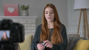 Young red-haired girl blogger, smiling, talking at the camera, showing a new purchase, cosmetics, Eyeshadow Pallet, home comfort in the background. 60 fps
