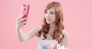 beauty woman take shopping bag and selfie on the pink background
