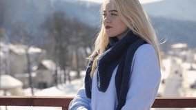 Young woman in sweater and scarf posing on a bridge at winter day