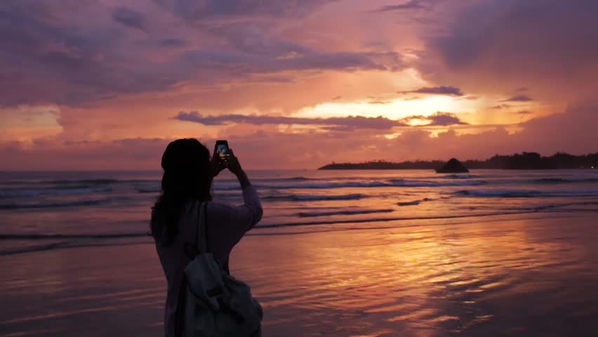 Girl takes a photo of beautiful sunset. Royalty-Free Stock Footage #1009073726