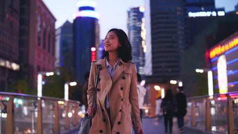 slow motion  of one pretty happy young asian woman walking in the city street  at evening