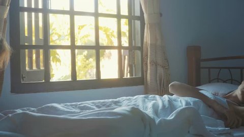 Cute little daughter wakes her mother at morning in slow motion. Funny video about little cute girl jumps on the bed where sleep her mum and then jumps to mother's stomach and mom is suddenly awakes