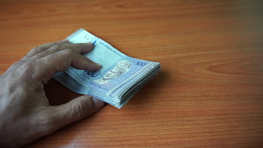 Malaysian currency (MYR): Hand is calculating Ringgit Malaysia currency notes. There is a hundred ringgit of malaysia that is stacked on the table. | Shutterstock HD Video #1009078610