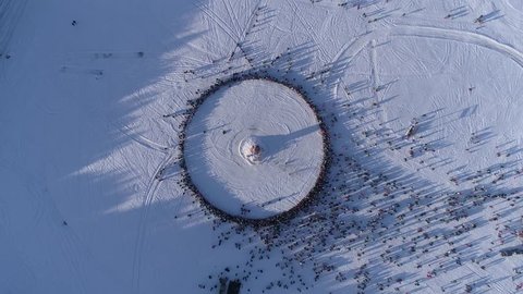Circle of people which watch burning of dummy during celebration of Russian traditional holiday Maslenitsa. Footage. Aerial view