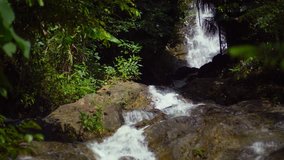 Whitewater tumbles playfully over a rocky. natural waterfall in a jungle nature area in Phuket. Thailand. 4k Ultra HD video with sound.