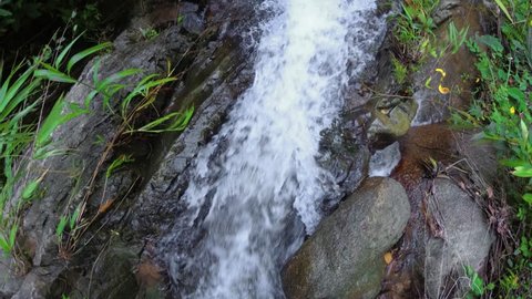 Water tumbles along a rocky. natural waterfall in a remote rainforest wilderness area on the island of Phuket. Thailand. 4k video with sound.