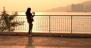 Woman taking photo with cellphone in golden sunset
