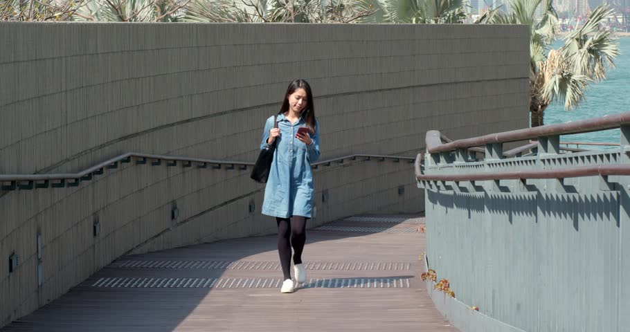 Woman use of mobile phone and walk in the street