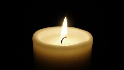 Closeup of burning candle isolated on black background.