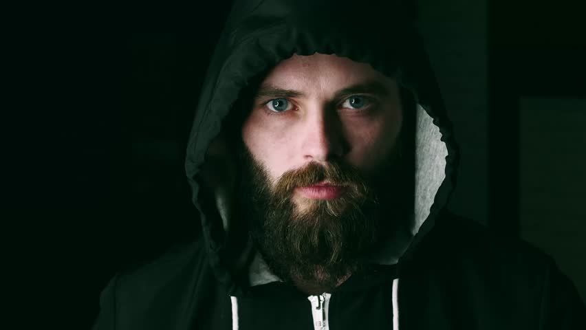 Portrait of a young bearded man in the hood with a serious expression who eats burger on camera in 4k resolution in slow motion Royalty-Free Stock Footage #1009091696