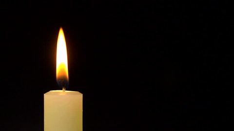 A single white candle burning. As the flame flickers and goes out, the wick produces lots of smoke.
