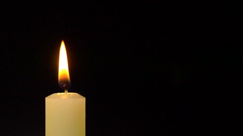 A single white candle burning. As it is blown out the smoke glows white.