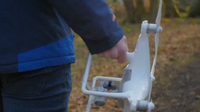 A person in a blue jacket goes with a drone through the forest in slowmotion