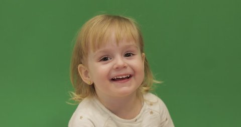 Funny cute child laughs. Beautiful two years old girl. Cute blonde child. Brown eyes. Close up. Green screen background