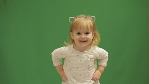 Funny cute child dancing. Beautiful two years old girl. Cute blonde child. Brown eyes. Close up. Slow motion. Green screen background