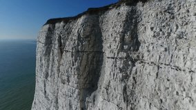 Aerial drone footage of The White Cliffs of Dover and South Foreland Lighthouse moving up and close past the bright white chalk cliffs turning right slowly showing the modern white lighthouse 4k
