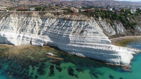 Aerial bird view flight towards Stair of the Turks in Italian Scala dei Turchi rocky cliff on coast of Realmonte near Porto Empedocle southern Sicily Italy it has become popular tourist attraction 4k