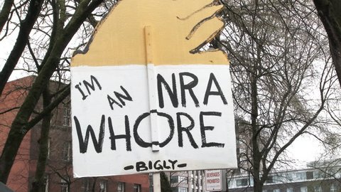 PORTLAND, OREGON / USA - MARCH 24, 2018: Person holds sign reading "I'm an NRA whore, bigly" poking fun a Donald Trump at March For Our Lives.