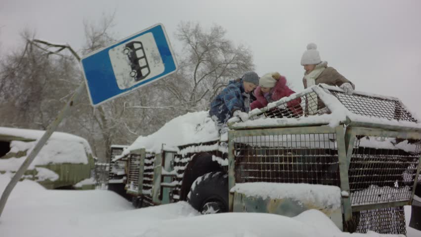 Children play on military equipment. Military Armored Personnel Carrier. The war in Donetsk. Broken military equipment on the streets of the city. A sign of a bus stop punctured by bullets.