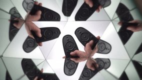 A person switches the TV channels by the remote control. Television mass media. Broadcast news and entertainment programs. Hand with TV remote control. Kaleidoscopic reflection in the mirror