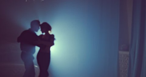 Young couple dance in a dark room with smoke. Slow motion. Silhouette