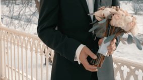 Groom dressed in black suit, white shirt  with wedding bouquet. Anonymous man. Slow motion video footage. Groom waiting his wife.