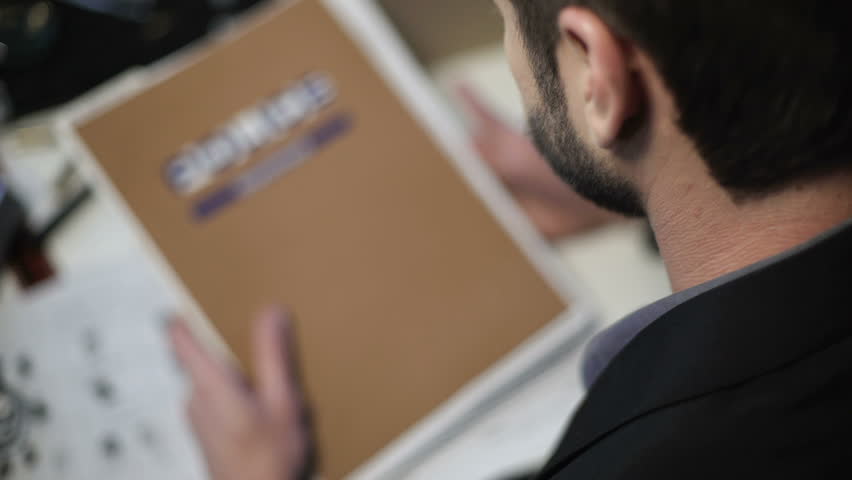 Detective searching paper with fingerprints among reports and other documents