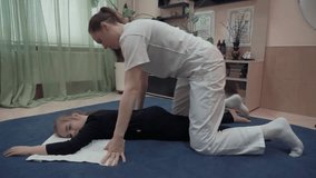 Masseuse makes yumeiho massage to child pressing on her back. This oriental therapy is a complex set of manual procedures and physical exercises