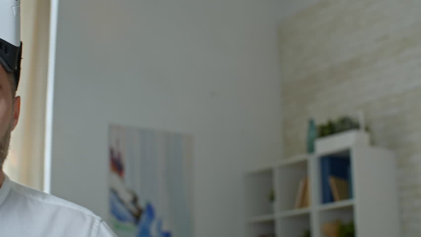 Medium shot with PAN of bearded middle-aged man posing for camera, then putting on VR headset