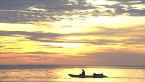 couple Kayaking in  the sea with bright gold sunset colour sky background cinemagraph clip