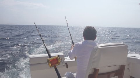 Slow Motion Rear View Of Man Getting Ready For Big Game Fishing On Open Sea