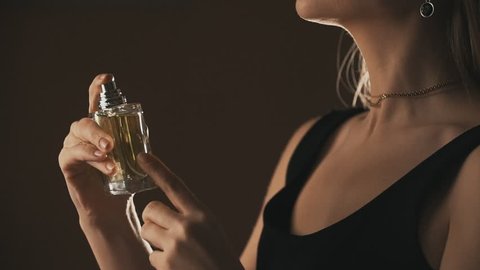 Sensual girl spraying fragrance in slow motion, with scent particles. Concept of sensual feminine scent.