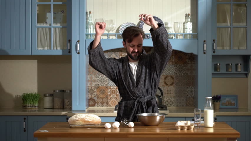 Portrait of amusing energetic guy 30s listening to music and dancing at home kitchen, while cooking breakfast omelet in slow motion | Shutterstock HD Video #1009163006