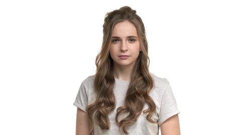 Studio portrait of hesitating woman in casual t-shirt thinking or counting pros and cons, isolated over white background closeup. Concept of emotions