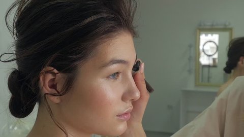Young beautiful woman applying make-up by make-up artist 4k