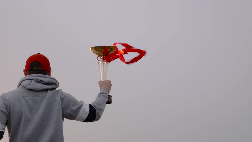 Young man with winner cup and red lines on the wind