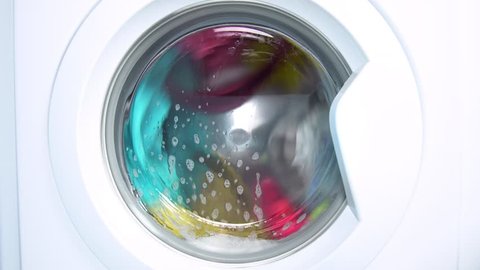 Washing machine washes colored clothing and sheets. Cylinder spinning. Nobody