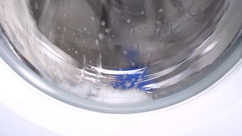 Washing machine washes white clothing and sheets. Cylinder spinning. Nobody