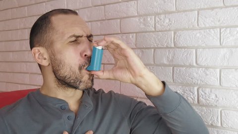 Asthma. A man with an inhaler.
