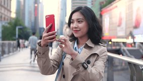 Pretty happy young asian woman using mobile phone video chatting in the Chinese city of Chengdu at afternoon in slow motion